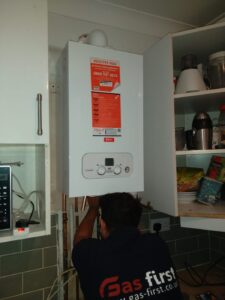 Gas Safe registered engineer fitting a new Main combi boiler in a kitchen in Dagenham, East London